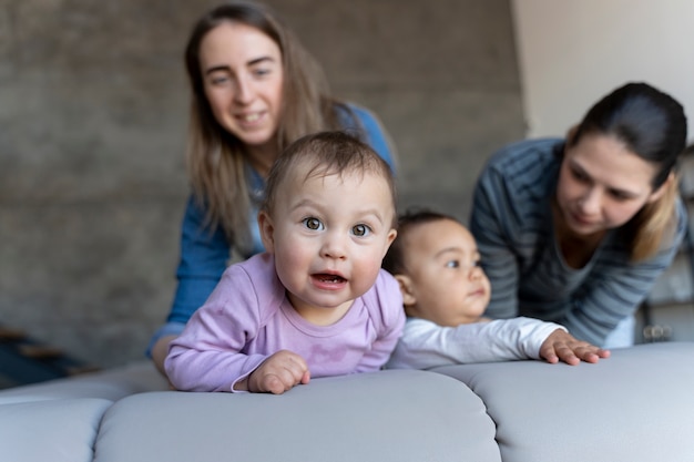 Photo gratuite bébés mignons rampant sur le canapé pendant que leurs mères regardent