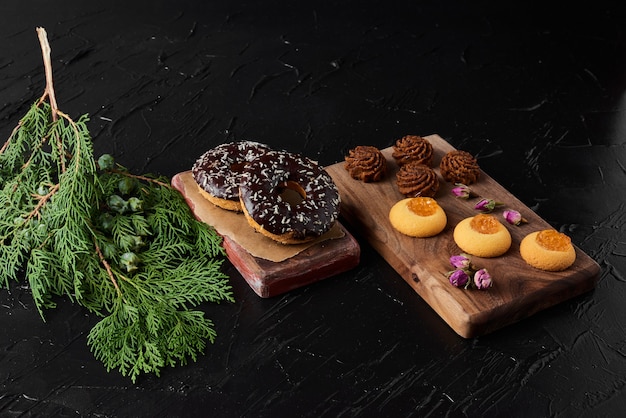 Beignets Au Chocolat Sur Une Planche De Bois Avec Des Pralines Et Des Biscuits Au Beurre.