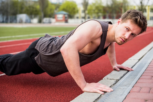 Photo gratuite bel athlète masculin faisant des pompes sur piste de course