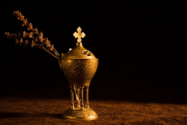 Bel encensoir d'église avec une branche séchée sur fond noir