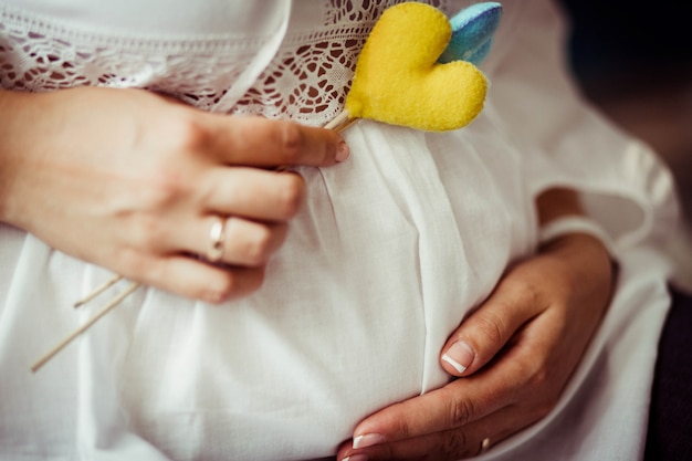 Bel et gentil ventre enceinte et coeur jaune sur le bâton