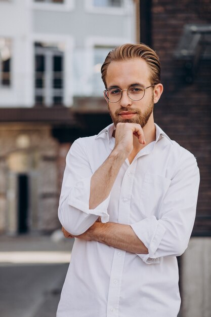 Bel homme d'affaires en chemise blanche marchant dans la rue