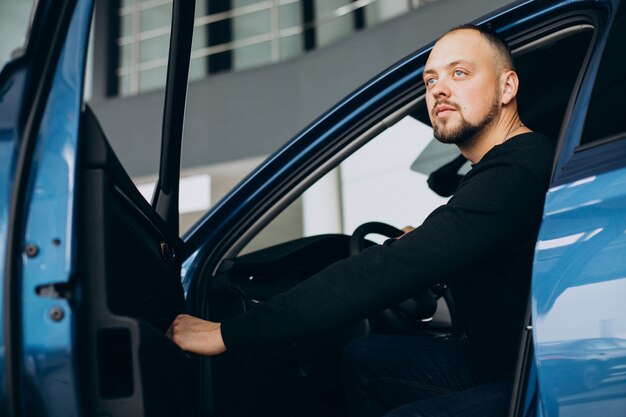 Bel homme d'affaires choisissant une voiture dans une salle d'exposition de voiture