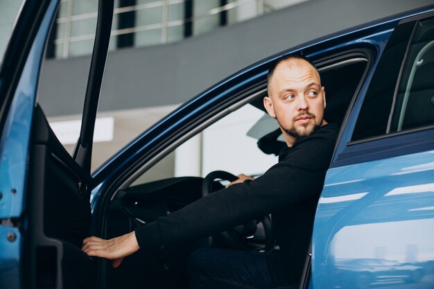 Bel homme d'affaires choisissant une voiture dans une salle d'exposition de voiture