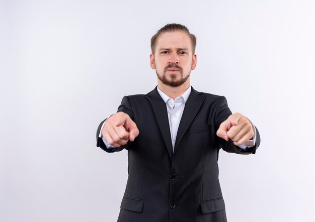 Bel homme d'affaires portant costume à la confiance en pointant avec l'index à la caméra debout sur fond blanc