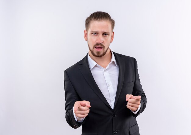 Bel homme d'affaires portant costume à la confiance en pointant avec l'index à la caméra debout sur fond blanc