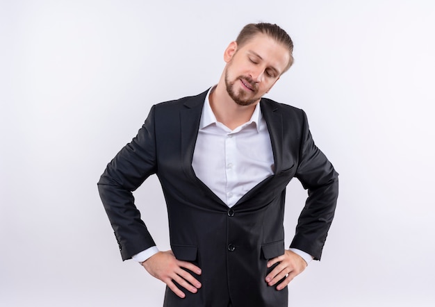 Bel homme d'affaires portant costume à côté avec une expression confiante debout sur fond blanc