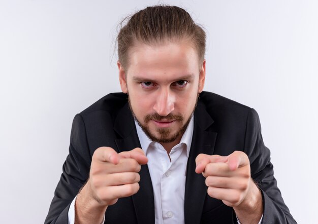 Bel homme d'affaires portant costume pointant avec l'index à la caméra avec une position sérieuse sur fond blanc