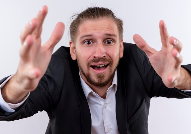 Photo gratuite bel homme d'affaires portant costume regardant la caméra avec les bras avec l'expression d'espoir debout sur fond blanc