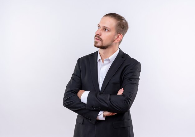 Bel homme d'affaires portant costume regardant de côté avec une expression pensive debout sur fond blanc