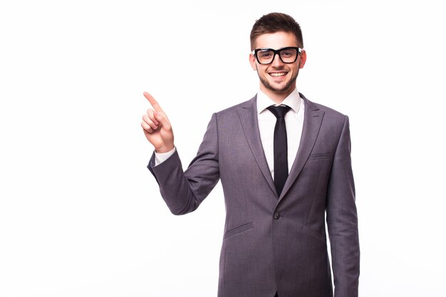 Bel homme d'affaires portant des lunettes debout avec la main dans la poche dans un sens et pointant vers le côté heureux sur fond de studio blanc