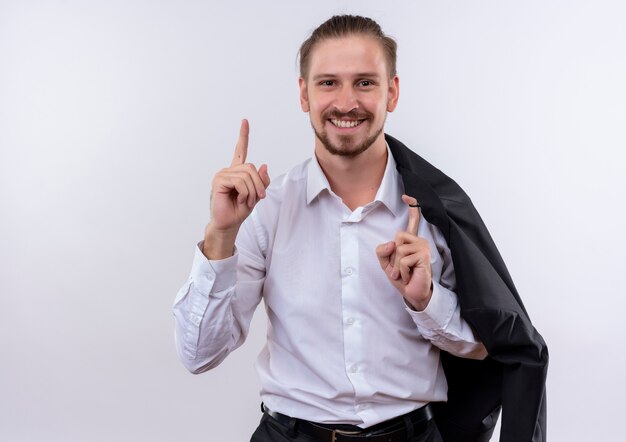 Bel homme d'affaires portant sa veste sur l'épaule regardant la caméra en souriant avec un visage heureux montrant l'index ayant une nouvelle idée debout sur fond blanc