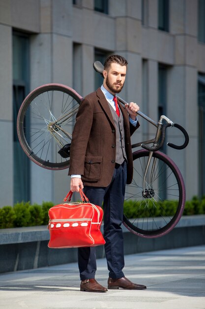 Bel homme d'affaires portant son vélo