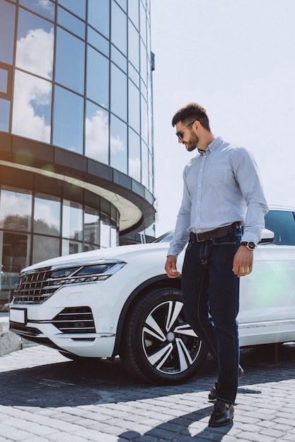 Bel homme d'affaires près de la voiture blanche