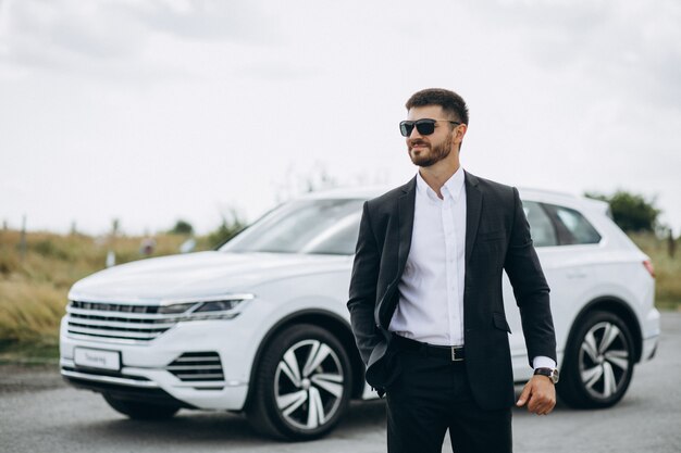 Bel homme d'affaires près de la voiture blanche