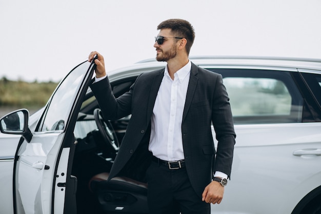 Bel homme d'affaires près de la voiture blanche