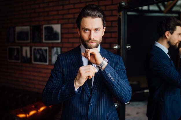 Un bel homme d'affaires regardant la caméra avec une montre à la main.