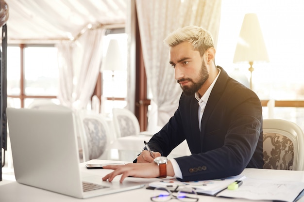 Bel homme d'affaires travaille sur l'ordinateur portable au restaurant