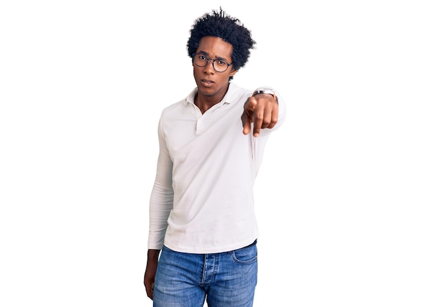 Photo gratuite bel homme afro-américain aux cheveux afro portant des vêtements décontractés et des lunettes pointant mécontent et frustré vers la caméra en colère et furieux contre vous