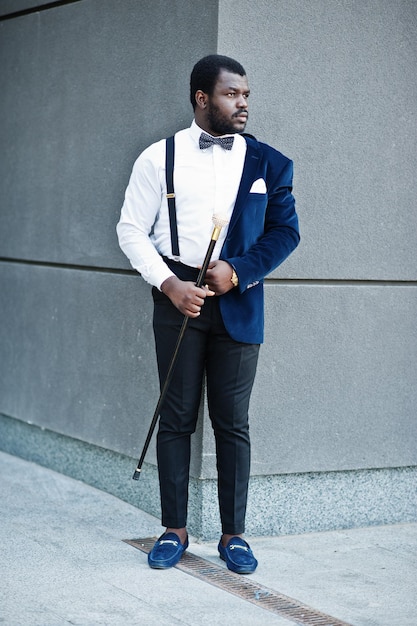 Bel homme afro-américain à la mode en tenue de soirée et noeud papillon avec canne