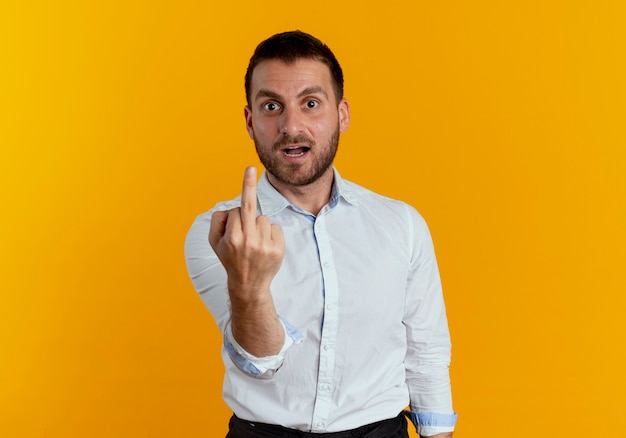 Bel homme agacé montre le majeur isolé sur un mur orange