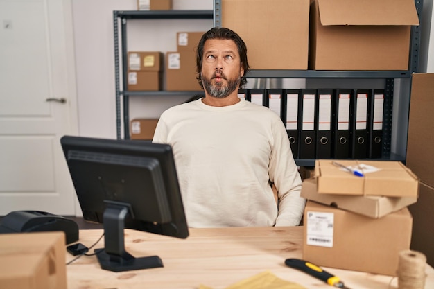 Bel homme d'âge moyen travaillant dans une petite entreprise de commerce électronique faisant un visage de poisson avec des lèvres folles et comiques geste drôle d'expression