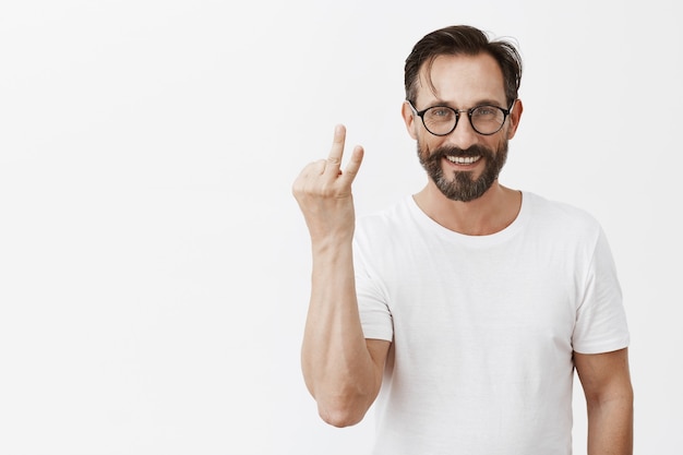 Bel homme d'âge mûr barbu heureux avec des lunettes posant