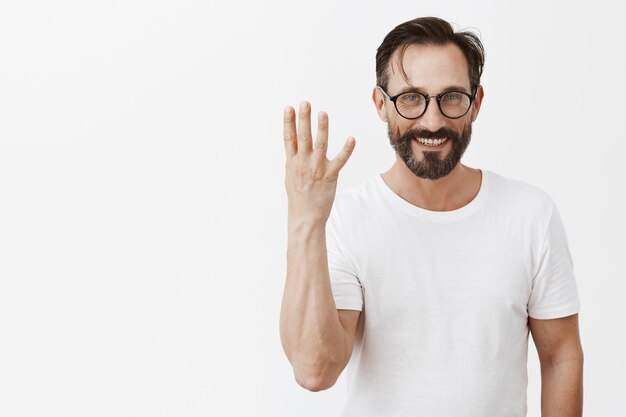 Bel homme d'âge mûr barbu heureux avec des lunettes posant