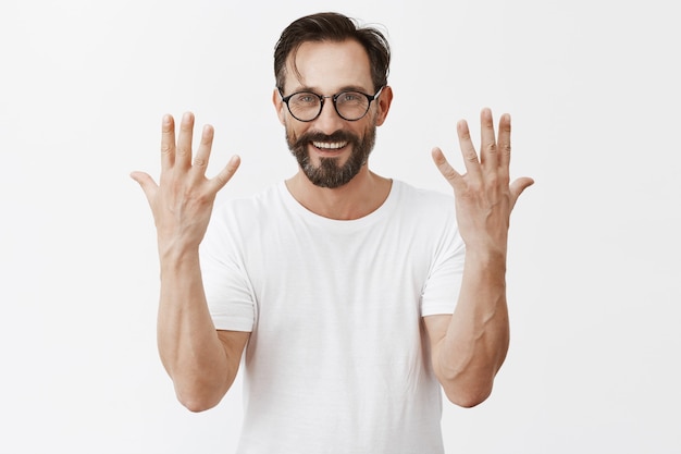 Bel homme d'âge mûr barbu heureux avec des lunettes posant