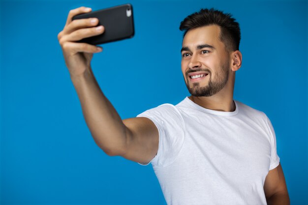 Bel homme américain prend un selfie et sourit à la caméra