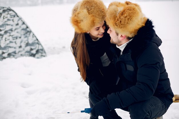 Photo gratuite bel homme assis sur une pêche d'hiver avec sa femme