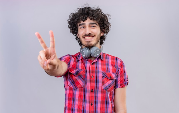 Un bel homme aux cheveux bouclés en chemise à carreaux montrant deux doigts