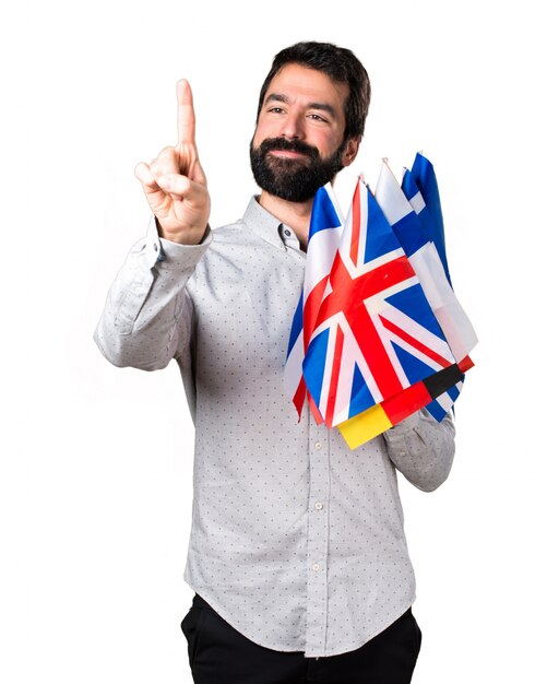 Un bel homme avec de la barbe tenant de nombreux drapeaux et touchant un écran transparent