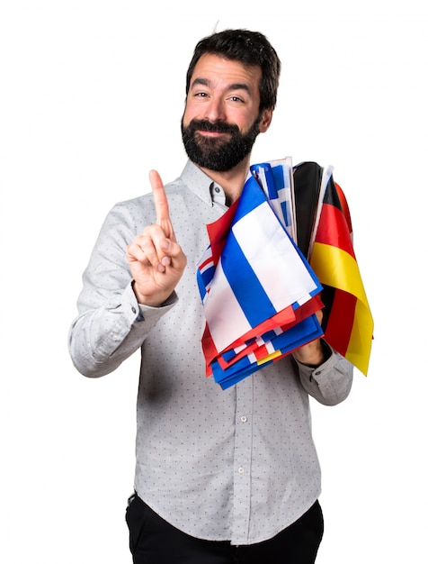 Photo gratuite un bel homme à la barbe tenant plusieurs drapeaux et comptant un