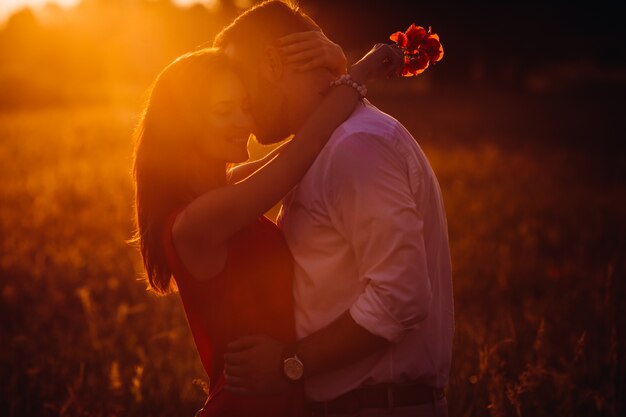 Bel homme barbu câlins femme en robe rouge tendre debout dans le champ de l&#39;été