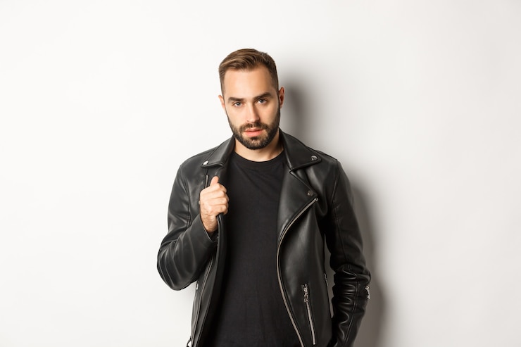 Photo gratuit bel homme barbu exprimant sa confiance, touchant sa veste en cuir et à la confiance en soi