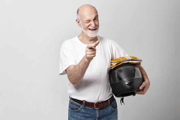 Bel homme barbu mature âgé émotionnel positif avec tête chauve tenant un casque de moto