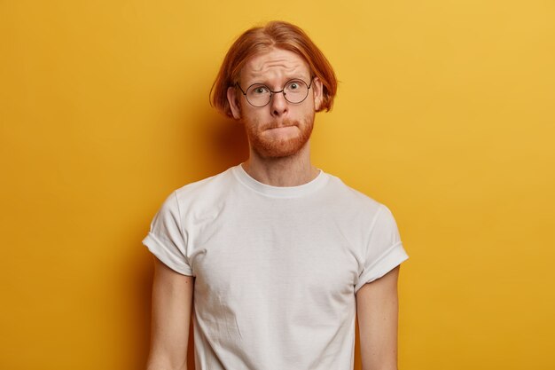 Bel homme barbu presse les lèvres, regarde avec une expression inquiète