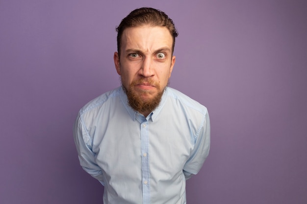 Bel homme blond en colère regarde à l'avant isolé sur mur violet