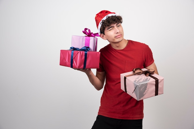 Bel homme en bonnet de Noel écoutant le son des cadeaux.