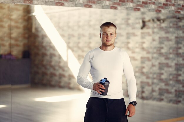 Bel homme avec une bouteille d'eau dans une salle de sport