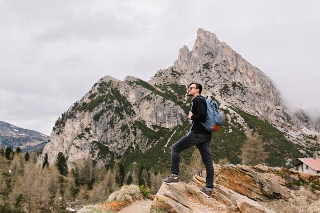 Bel homme brune se dresse sur le rocher en regardant avec admiration une vue imprenable sur la nature