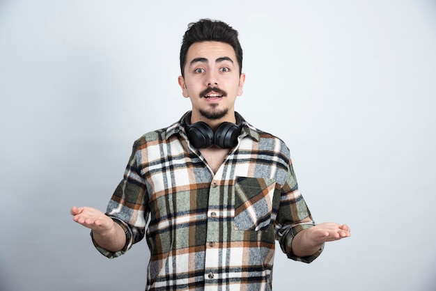 bel homme avec un casque debout sur un mur blanc.