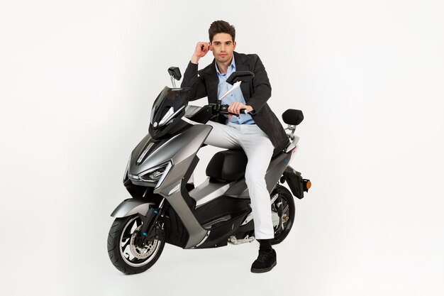 Bel homme à cheval sur scooter moto électrique isolé sur fond blanc studio