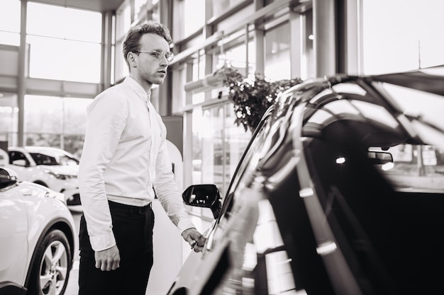 Bel homme choisissant une voiture dans une salle d'exposition