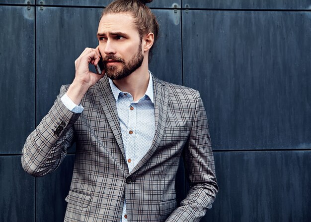 Bel homme en costume à carreaux gris parlant avec smartphone