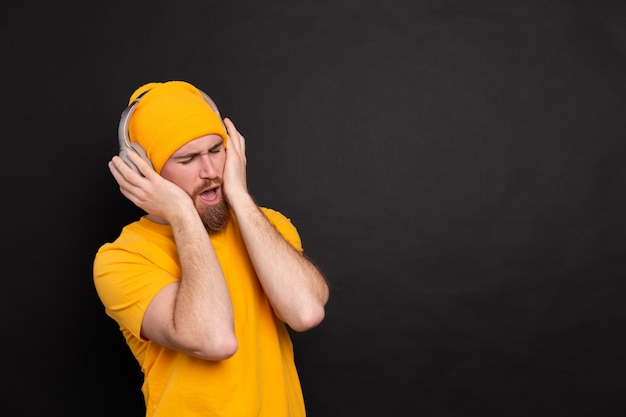 Bel homme en danse décontractée avec un casque isolé sur fond noir