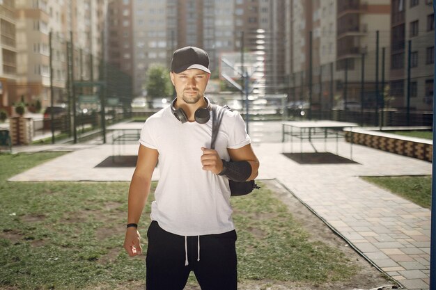 Bel homme debout dans un parc avec des écouteurs