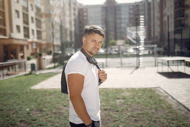 Bel homme debout dans un parc avec des écouteurs