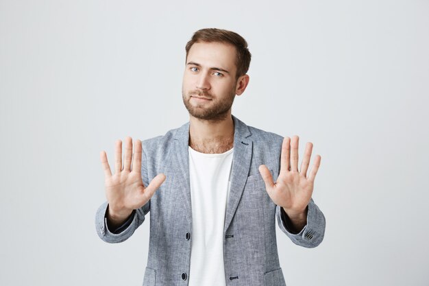 Bel homme élégant barbu montre des paumes, dites stop